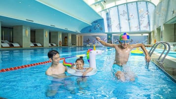 Una piscina techada, sombrillas, sillones reclinables de piscina