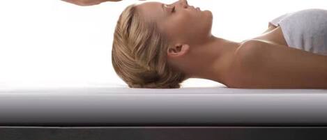 A person lying on a massage table in a poolside setting.