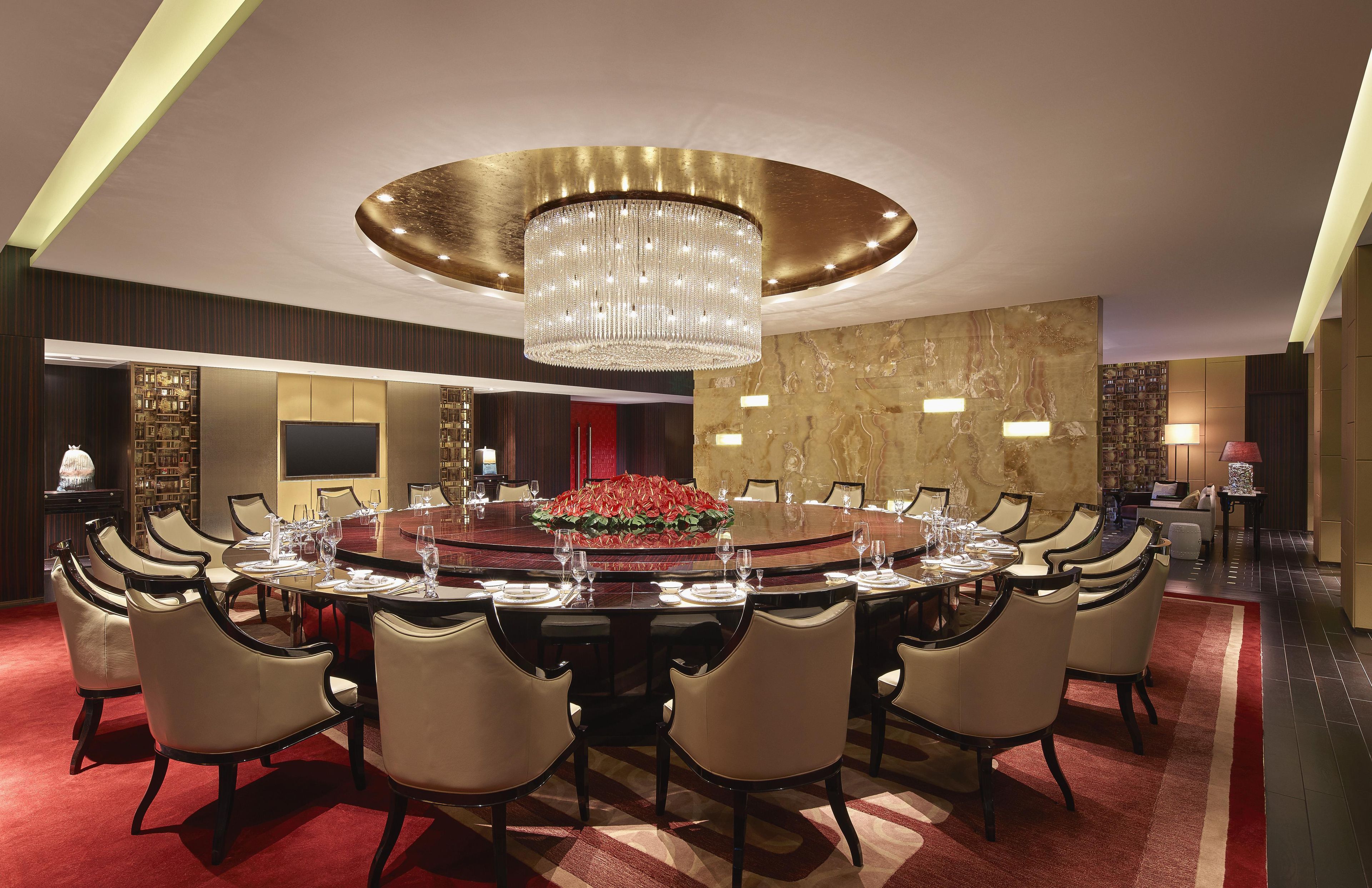 Un comedor formal con una mesa redonda grande, múltiples sillas y un candelabro.