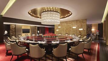 Un comedor formal con una mesa redonda grande, múltiples sillas y un candelabro.