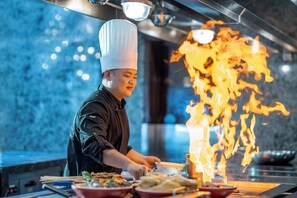 Un chef cuisinant avec des flammes, une cuisinière et un plan de travail.
