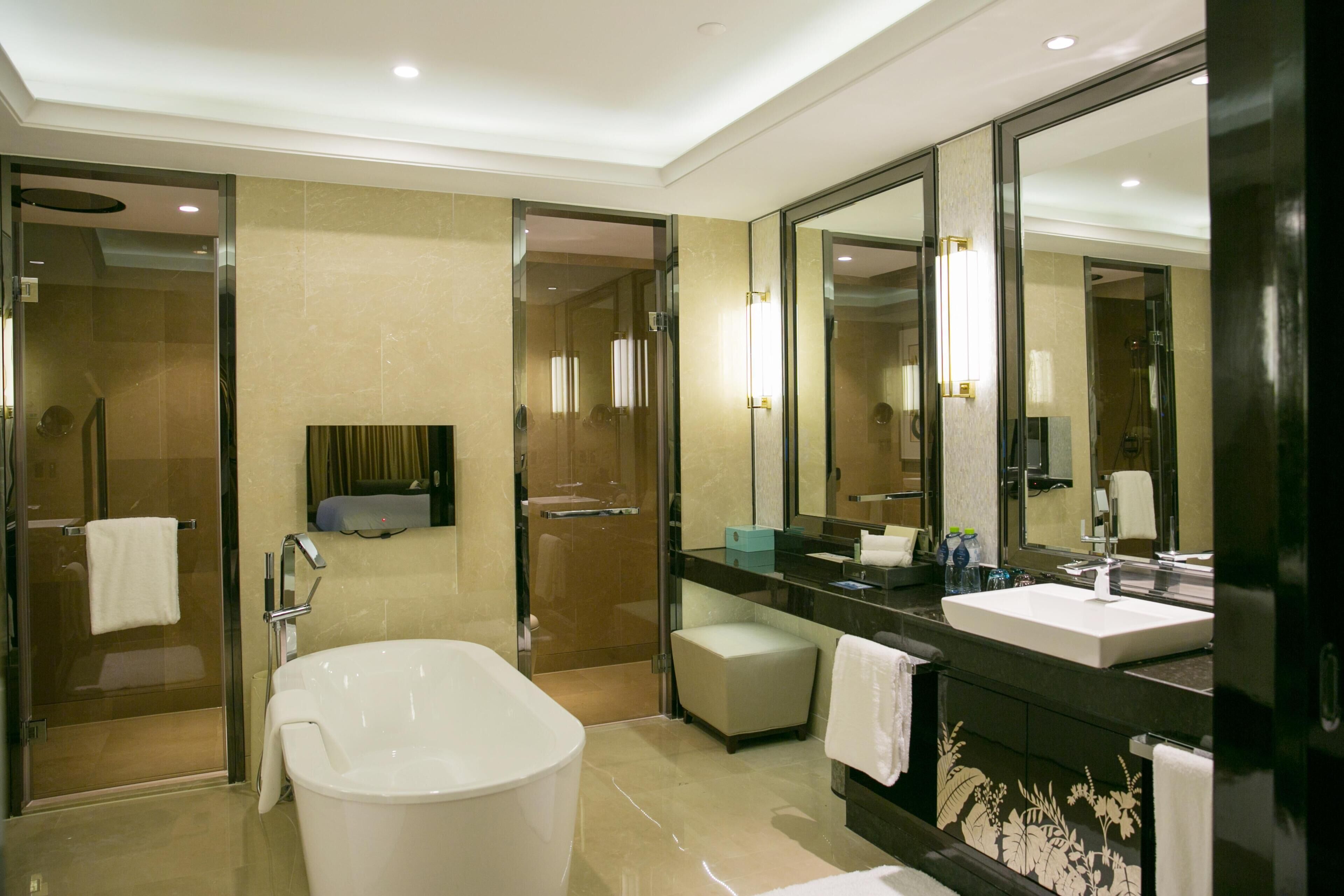 A modern bathroom with a large bathtub, a separate shower area, and a vanity with a mirror.