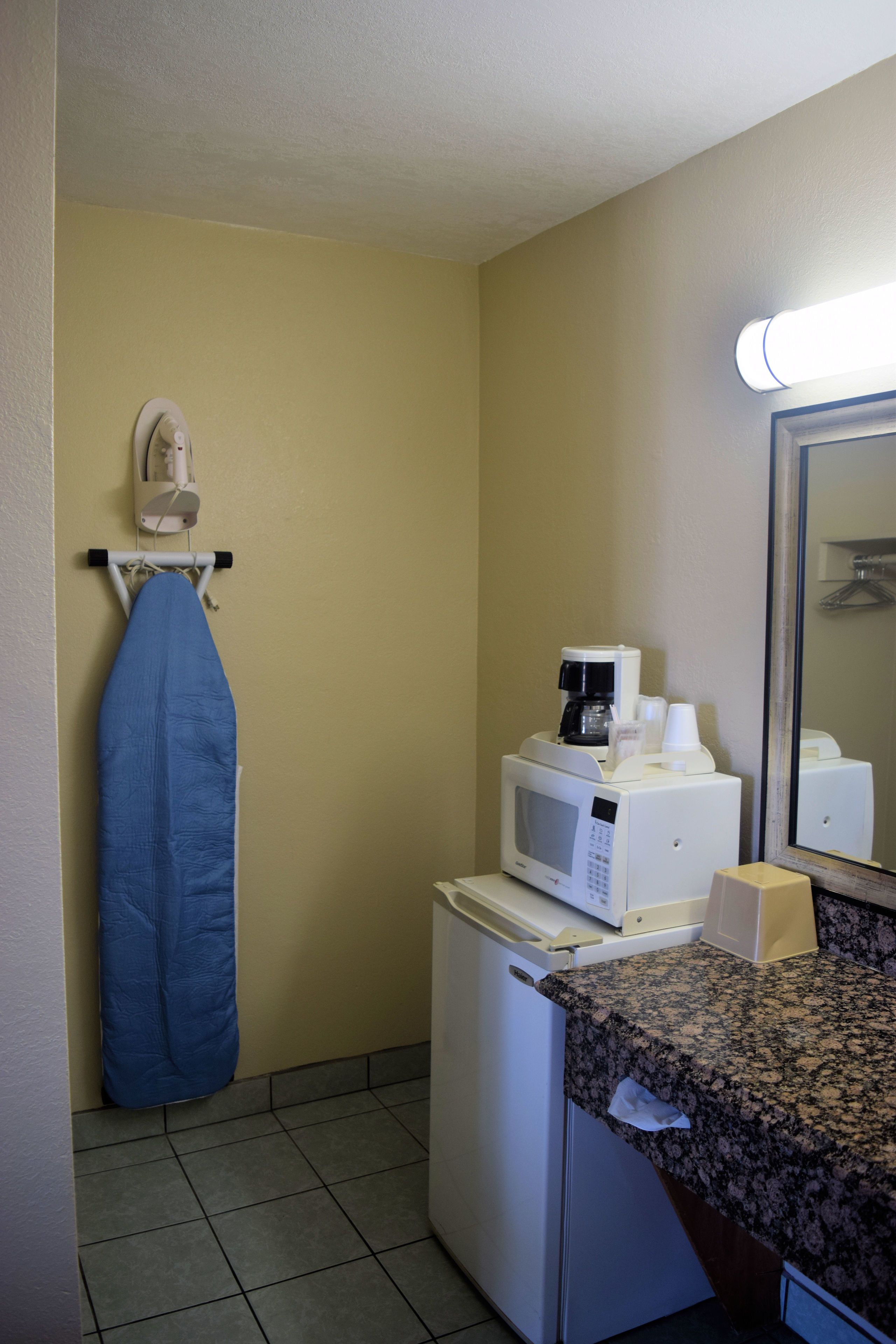 Habitación de hotel compacta con kitchenette, microondas, cafetera y espejo.
