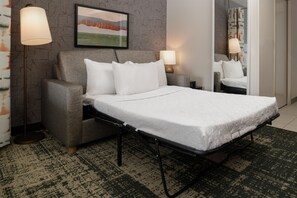 Una camera d'albergo con un letto, due abat-jour, un tappeto decorato e un quadro appeso alla parete.