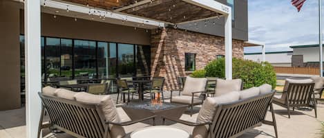 An outdoor patio with seating, a fire pit, and a view of the city.