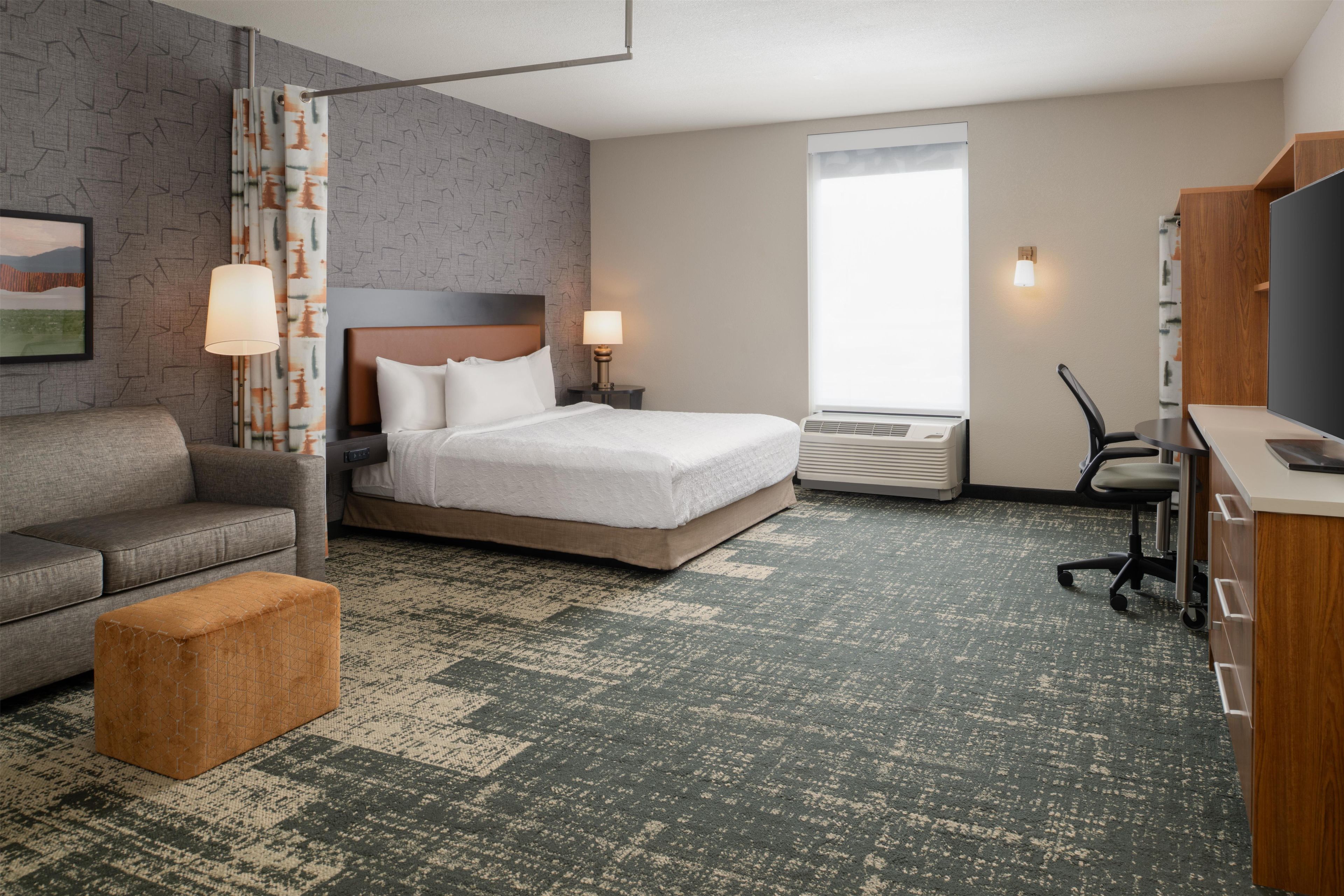 Une chambre d’hôtel équipée d’un lit, d’un bureau, d’une chaise, d’un canapé, d’une lampe et d’un téléviseur.