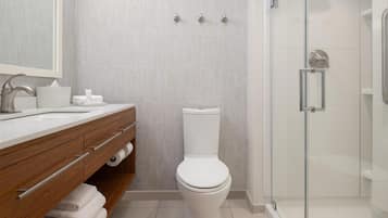 A modern bathroom with a wooden vanity, a toilet, and a glass shower enclosure.