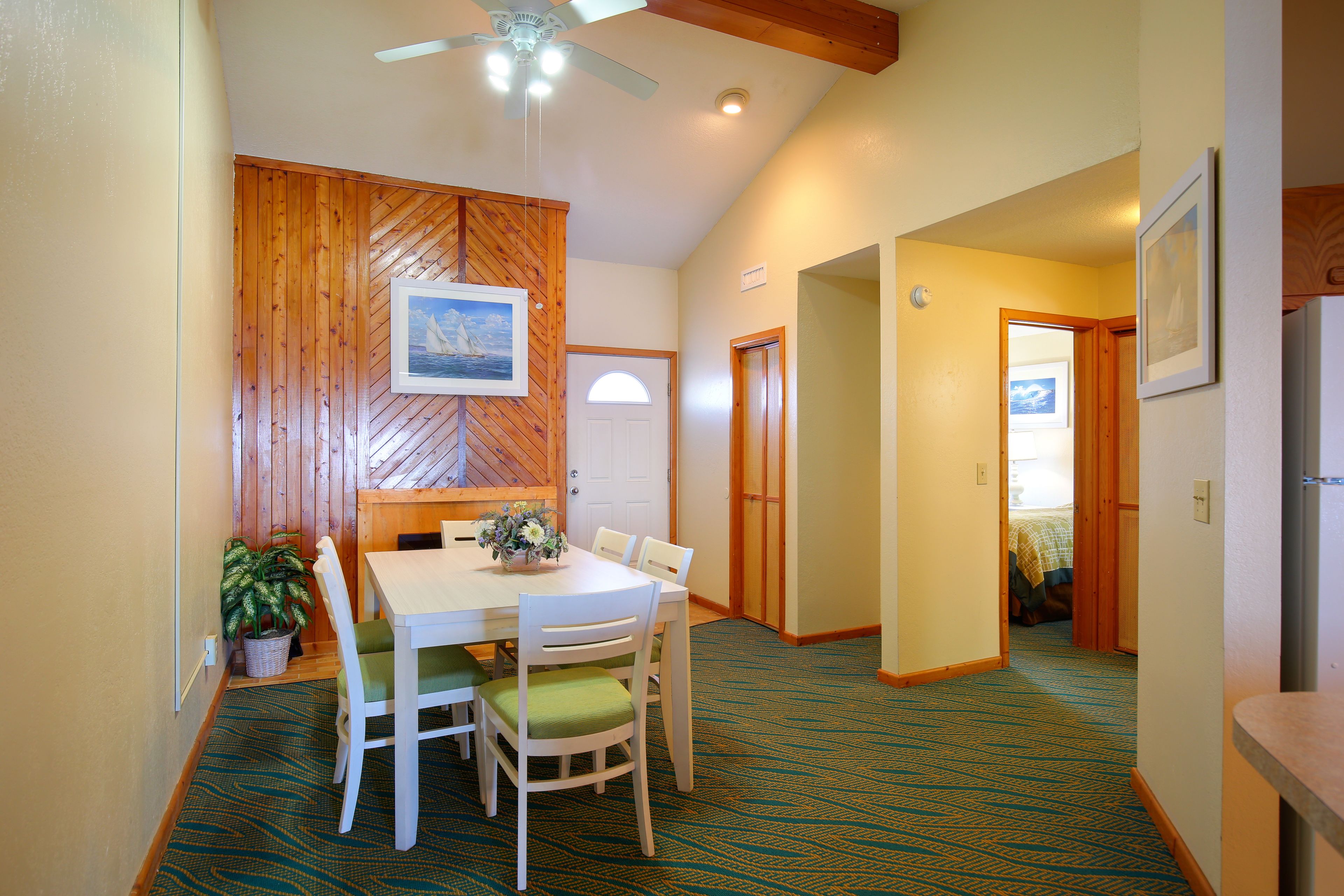 Un espace repas avec un mur en bois, un ventilateur de plafond et un tapis à motifs.