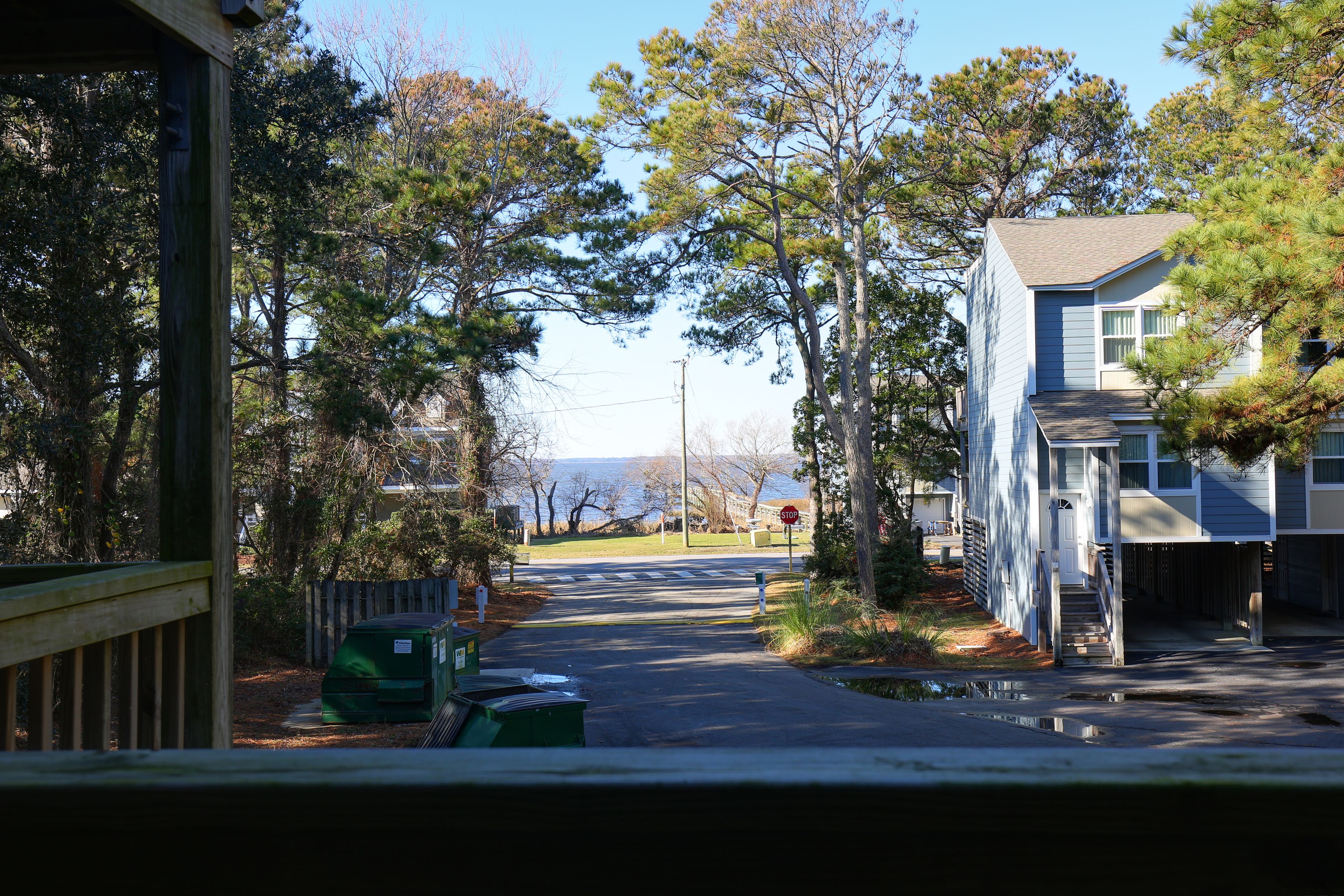 A residential street with houses, trees, and a stop sign.