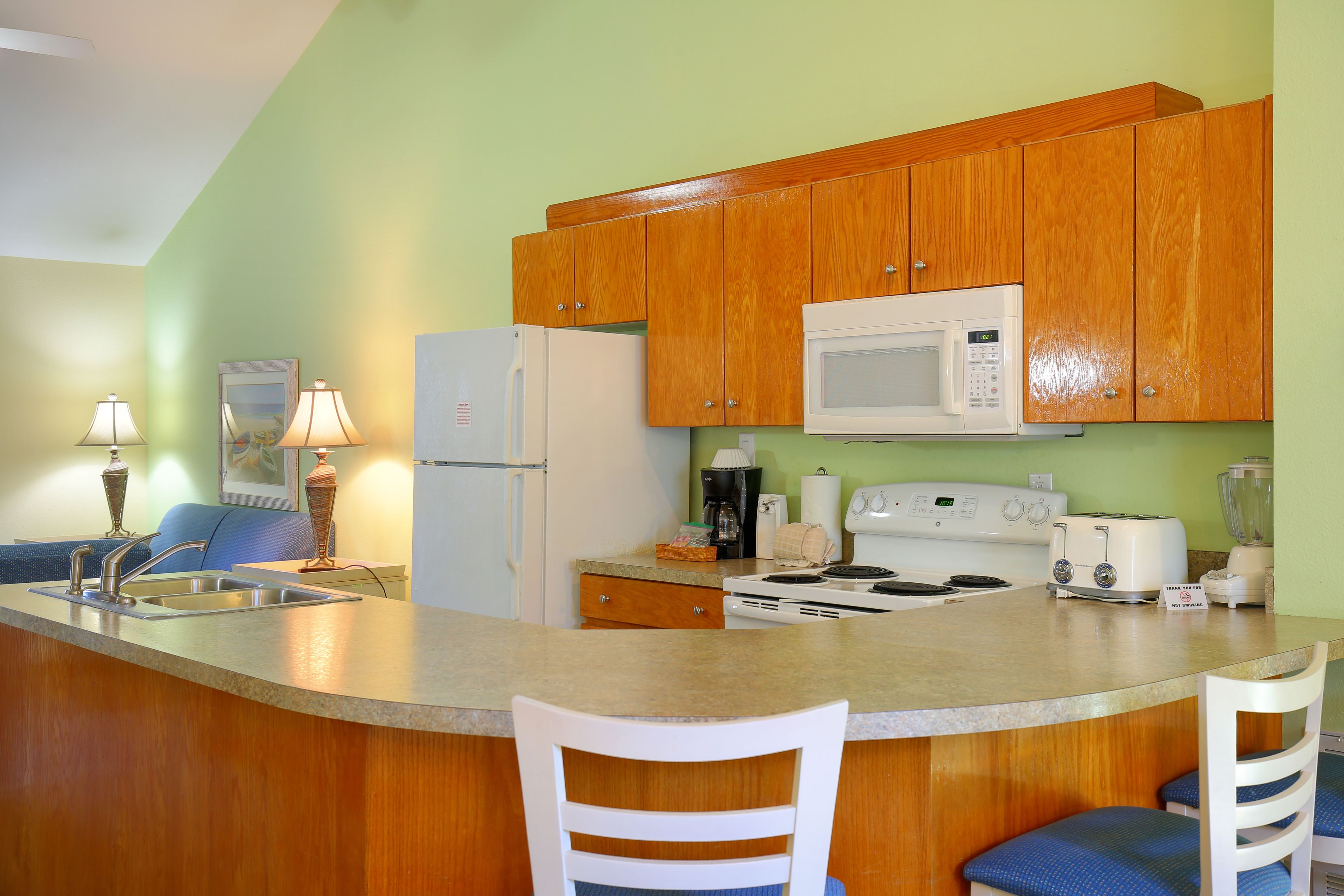 A kitchen with wooden cabinets, a microwave, a refrigerator, a stove, and a sink.