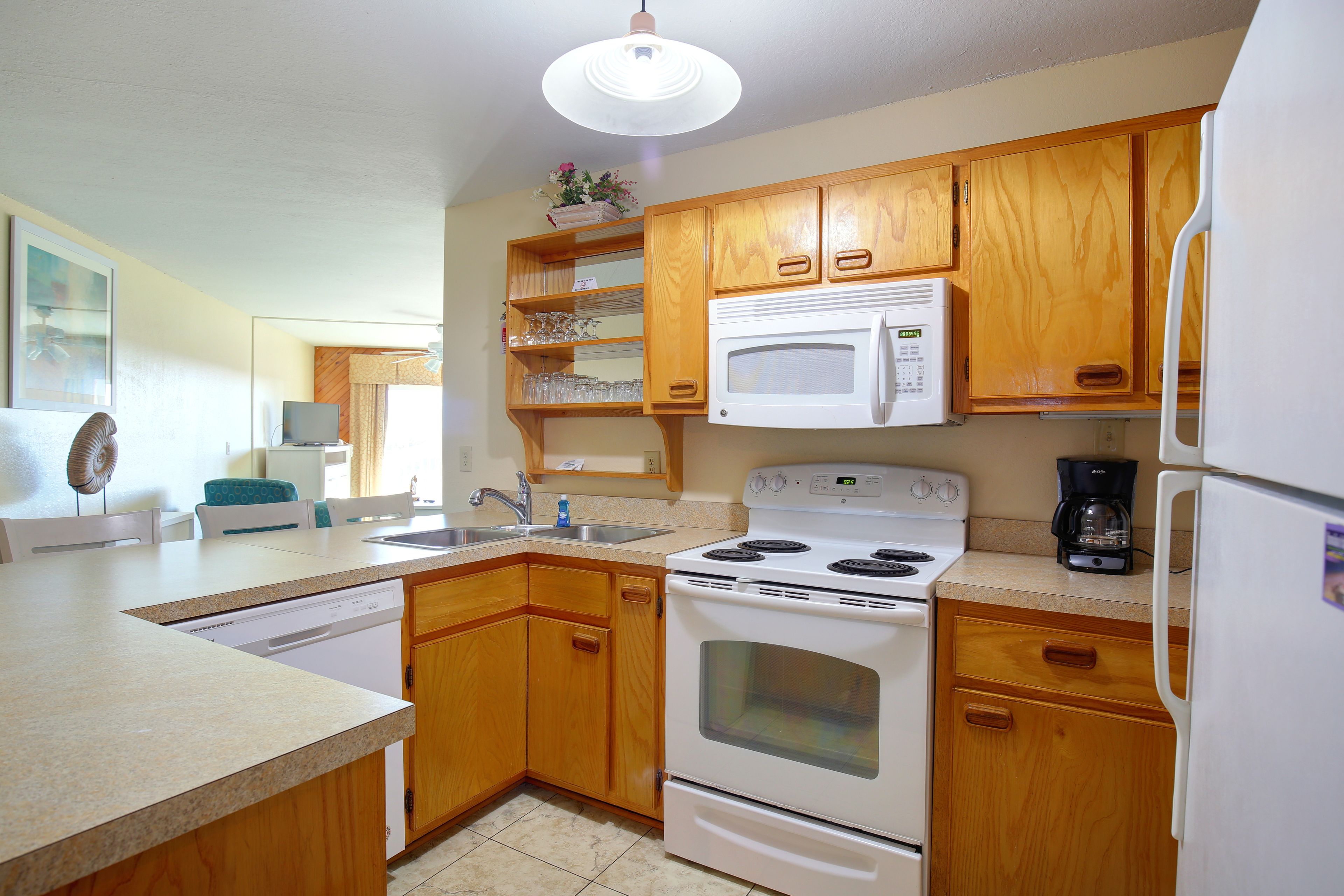 A kitchen with wooden cabinets, a white stove, a microwave, and a refrigerator.