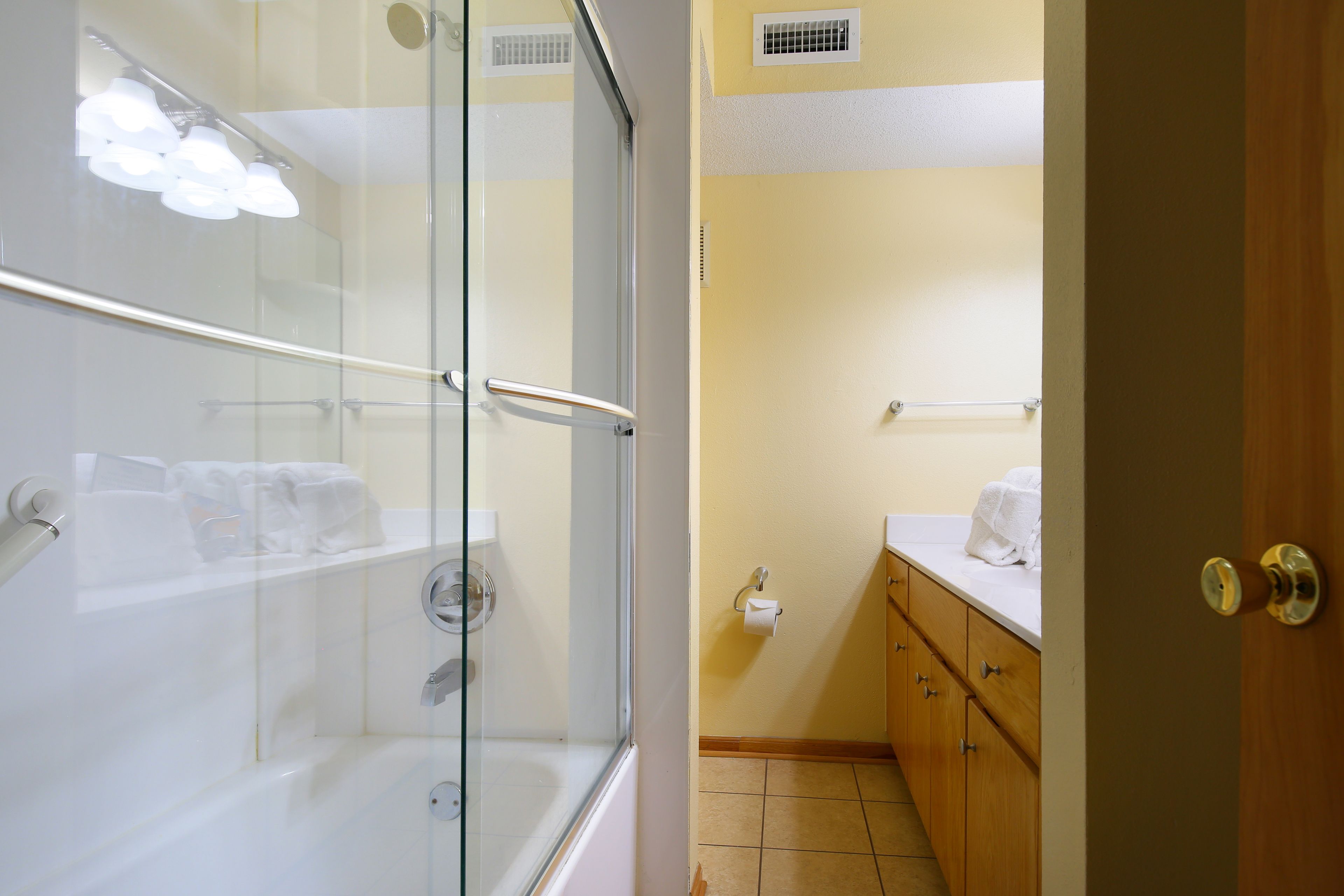 Une salle de bain avec une douche à parois de verre, un meuble-lavabo en bois avec un miroir et un porte-serviettes.