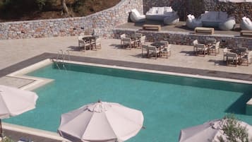 A pool area with lounge chairs and umbrellas, surrounded by stone walls.