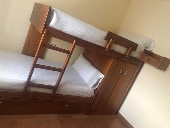 A bunk bed with a ladder, a small shelf, and a cabinet.