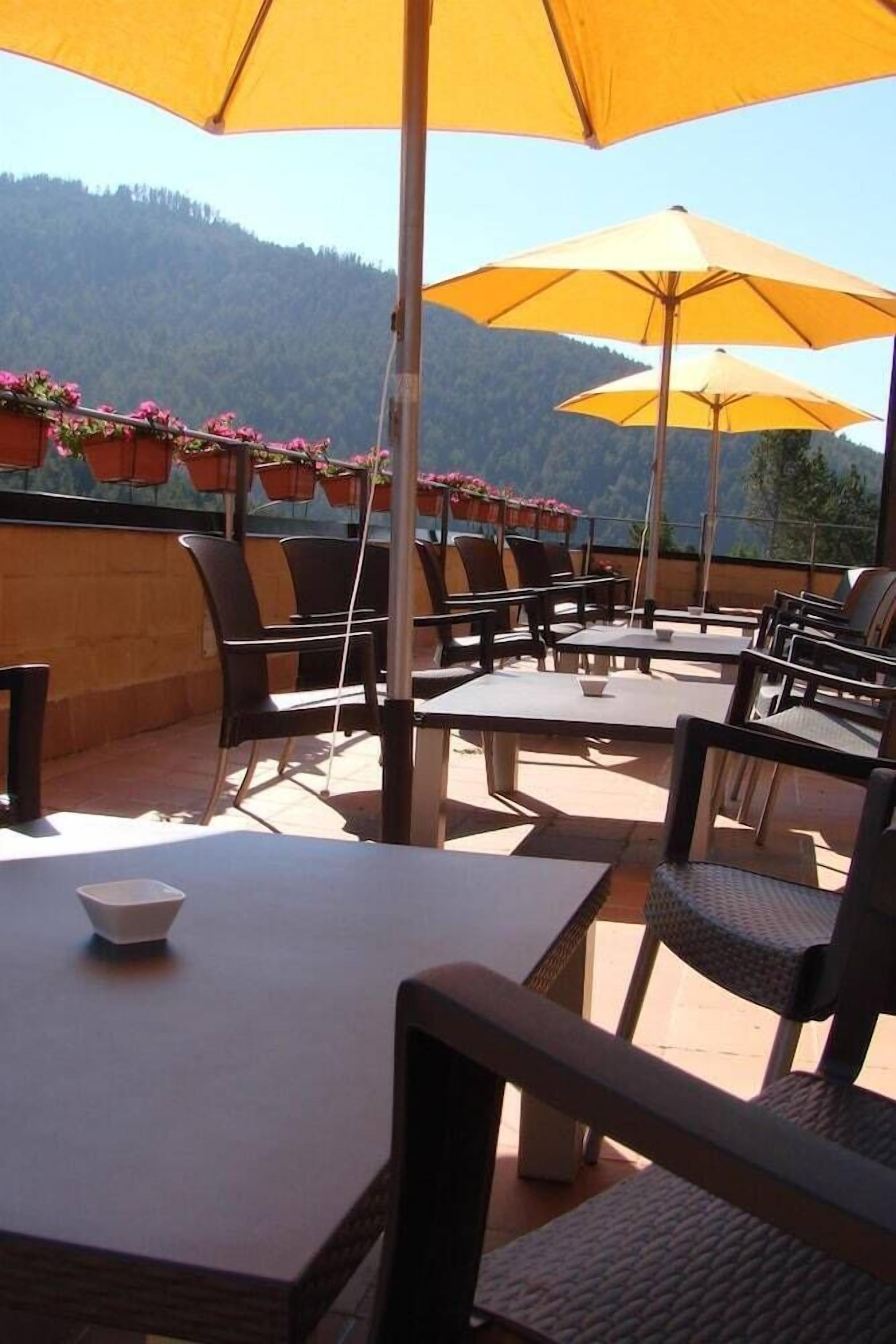 An outdoor patio with tables and chairs, yellow umbrellas, and flower planters.