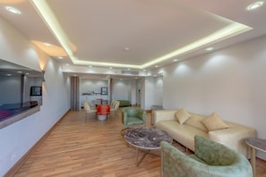 A modern living room with a sofa, armchairs, a coffee table, and a TV. - Hotel Titanic Beach Spa And Aqua Park (Hurghada)