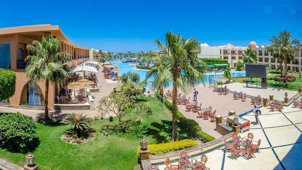 A resort with multiple swimming pools, outdoor seating areas, and palm trees. - Hotel Titanic Beach Spa And Aqua Park (Hurghada)