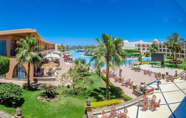 A resort with multiple swimming pools, outdoor seating areas, and palm trees. - Hotel Titanic Beach Spa And Aqua Park (Hurghada)