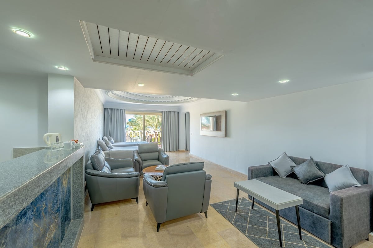 Uma sala de estar moderna com um sofá, poltronas, uma mesa de centro e uma televisão.