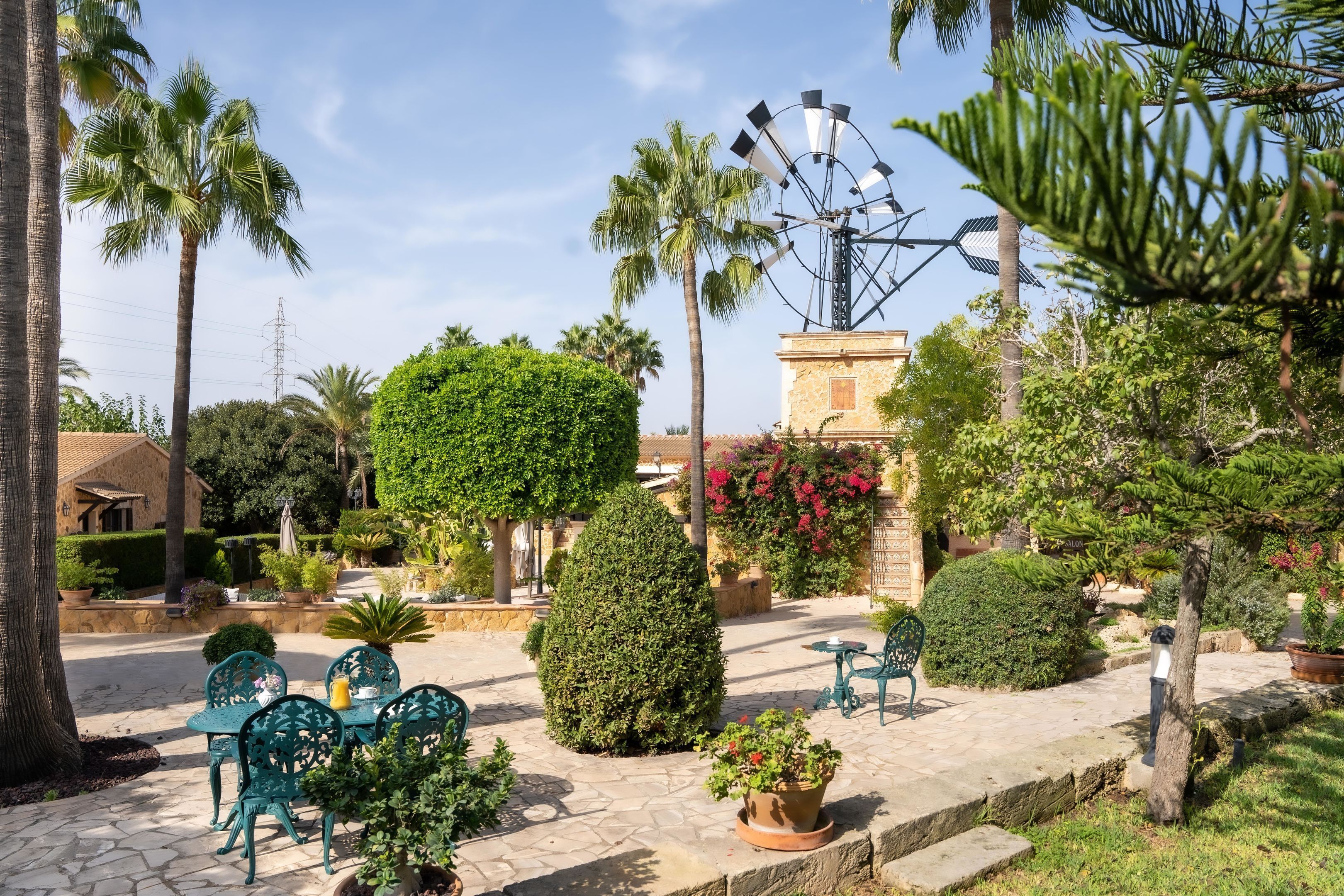 A courtyard with outdoor seating, palm trees, and a windmill.