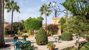 A courtyard with outdoor seating, palm trees, and a windmill.