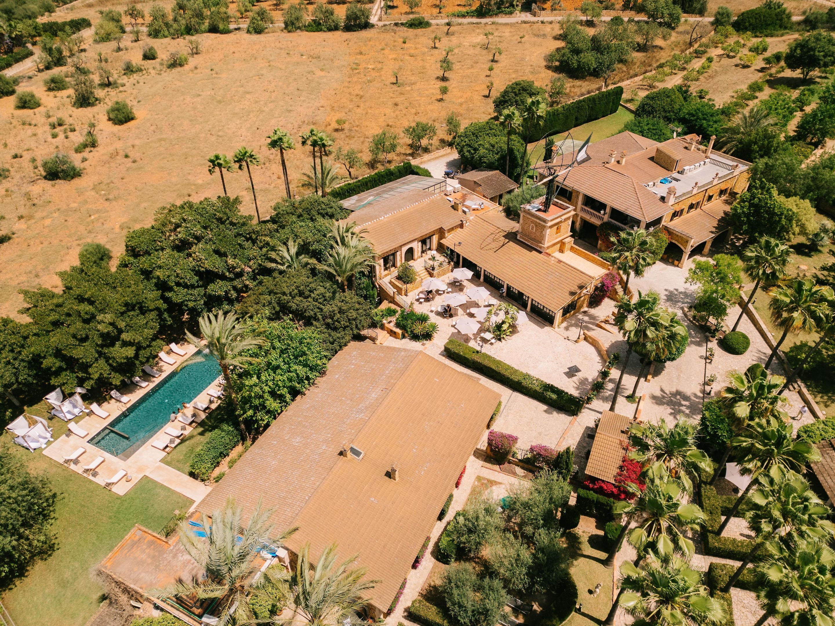 Een luchtbeeld van een resort met een zwembad, meerdere gastenkamers en weelderige beplanting.