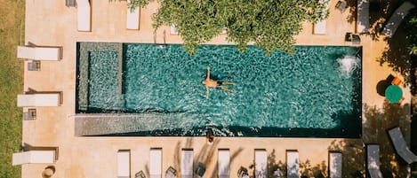 Una piscina al aire libre, sombrillas, sillones reclinables de piscina