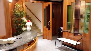 A modern kitchen with a granite countertop, wooden cabinetry, a vase of flowers, and a staircase leading to another room. - Albergo Ester di Fossi Laura (Rimini)