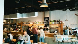 A bar area with patrons, a counter, and shelves of bottles. - Len KYOTO KAWARAMACHI – Hostel (Kyoto)