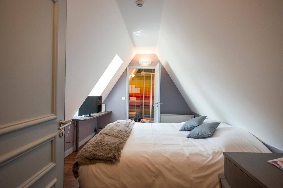 Une chambre à coucher avec un lit, une table de chevet et une fenêtre.