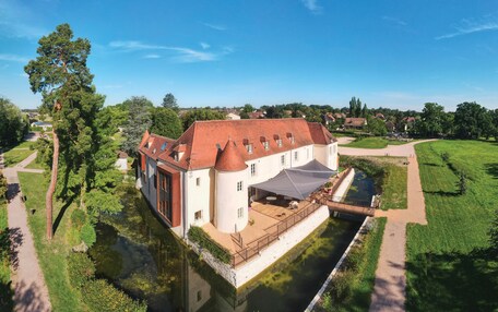A large, historic building with a courtyard, a water canal, and a paved walkway.