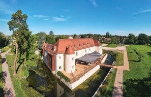 Un edificio grande e histórico con un patio, un canal de agua y un paseo pavimentado.