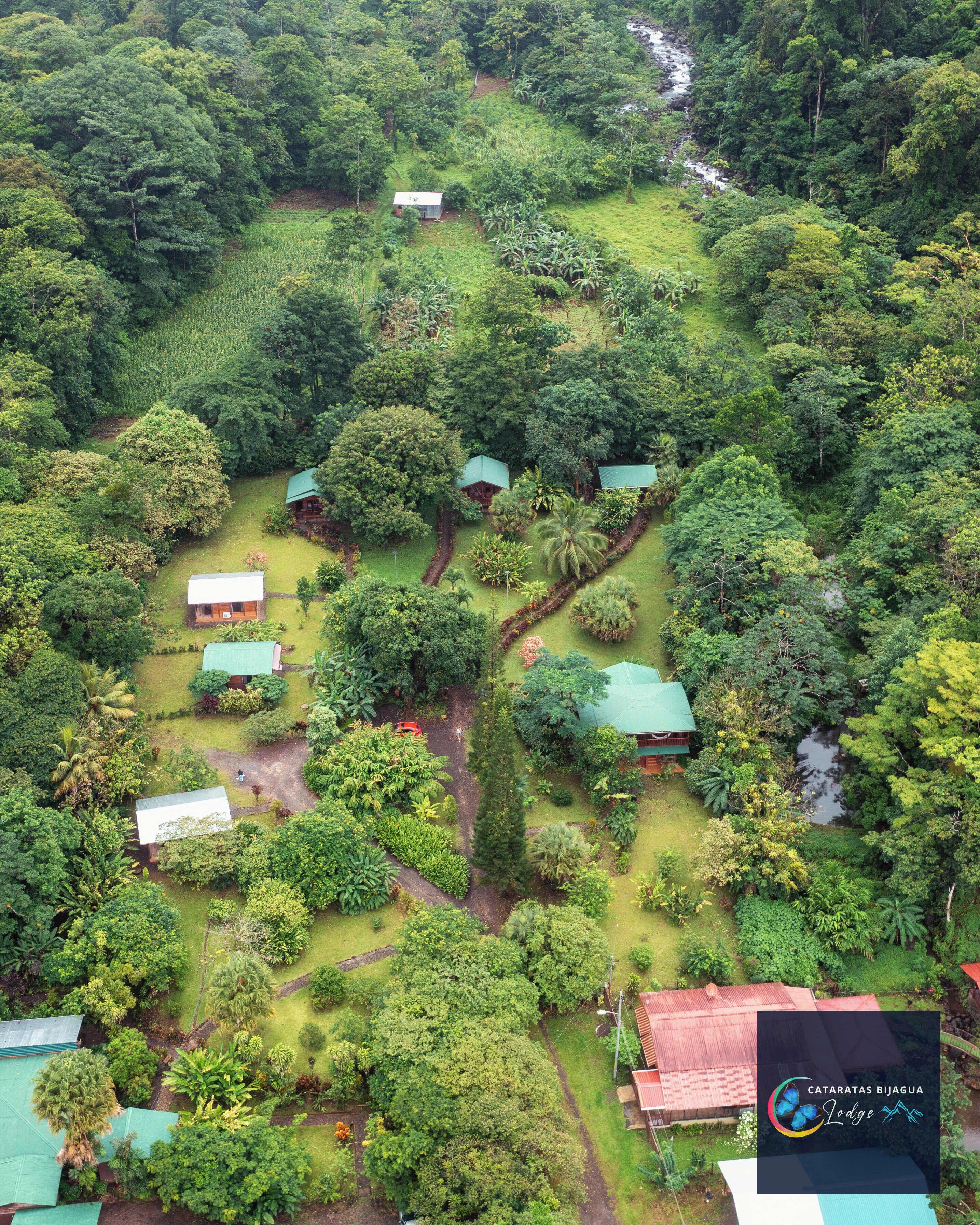 An aerial view of a lush, green landscape with several small buildings surrounded by dense vegetation.