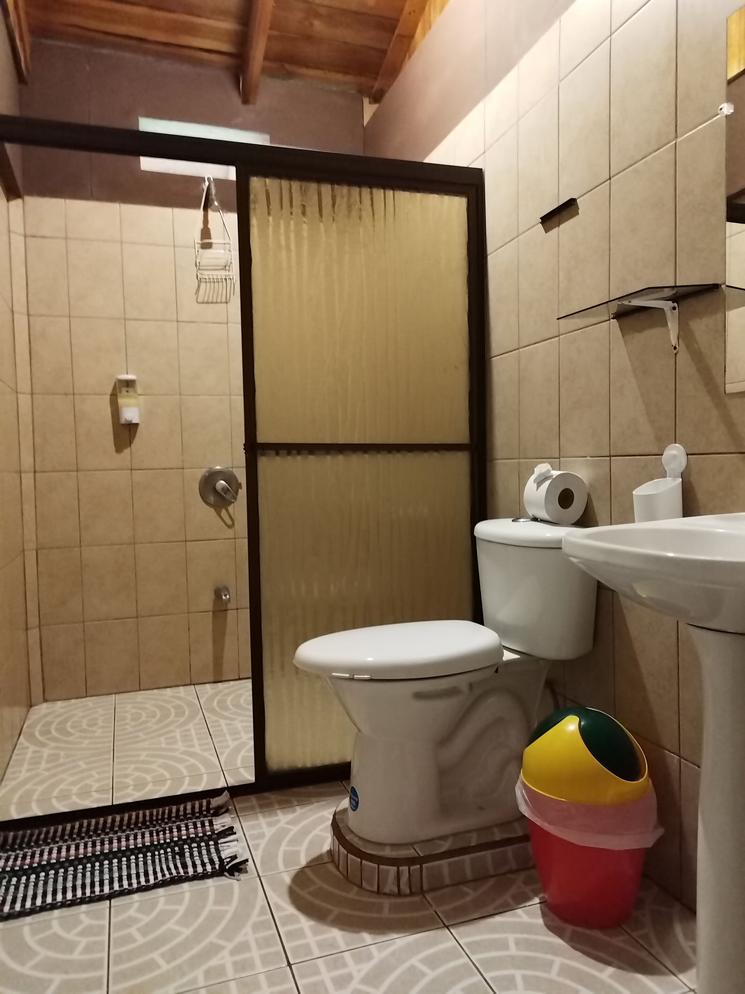A bathroom with a toilet, sink, and a trash bin.