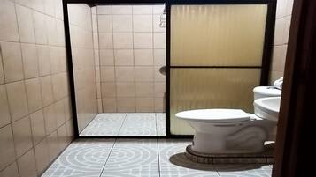 A bathroom with a toilet, a shower area, and patterned floor tiles.