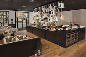 Uma área moderna de bar com diversas bebidas e petiscos, piso de madeira e um espaço de estar com mesas e cadeiras.