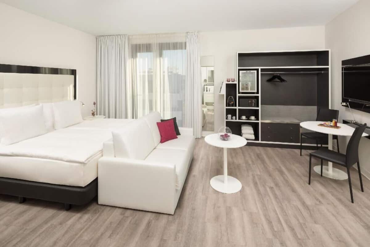 Une chambre d’hôtel moderne équipée d’un lit, d’un canapé, d’une table à manger et d’un téléviseur.