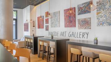 An art gallery with abstract paintings, a bar area, and seating.