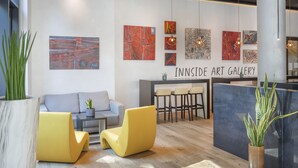An art gallery with modern furnishings, including a sofa, yellow chairs, and a reception desk. - INNSiDE by Meliá Frankfurt Ostend (Frankfurt)