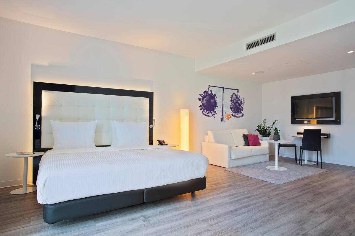 Une chambre d’hôtel moderne équipée d’un grand lit, d’un bureau, d’un canapé et d’une télévision.