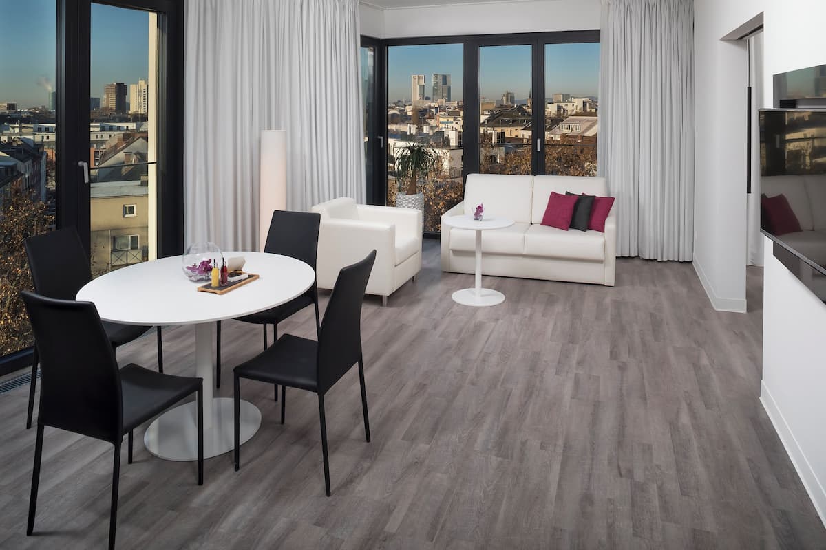 Un salon moderne avec un coin repas, de grandes fenêtres et une vue sur la ville.