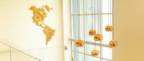 Een modern interieur met een glazen trap, een gouden wereldkaart aan de muur en hangende sferische lampen.