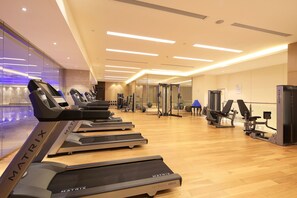 Uma academia com esteiras, aparelhos de musculação e bolas de exercício.