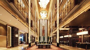 A spacious lobby with a central reception desk, high ceilings, and modern lighting fixtures. - Wyndham Grand Plaza Royale Huayu Chongqing (Chongqing)