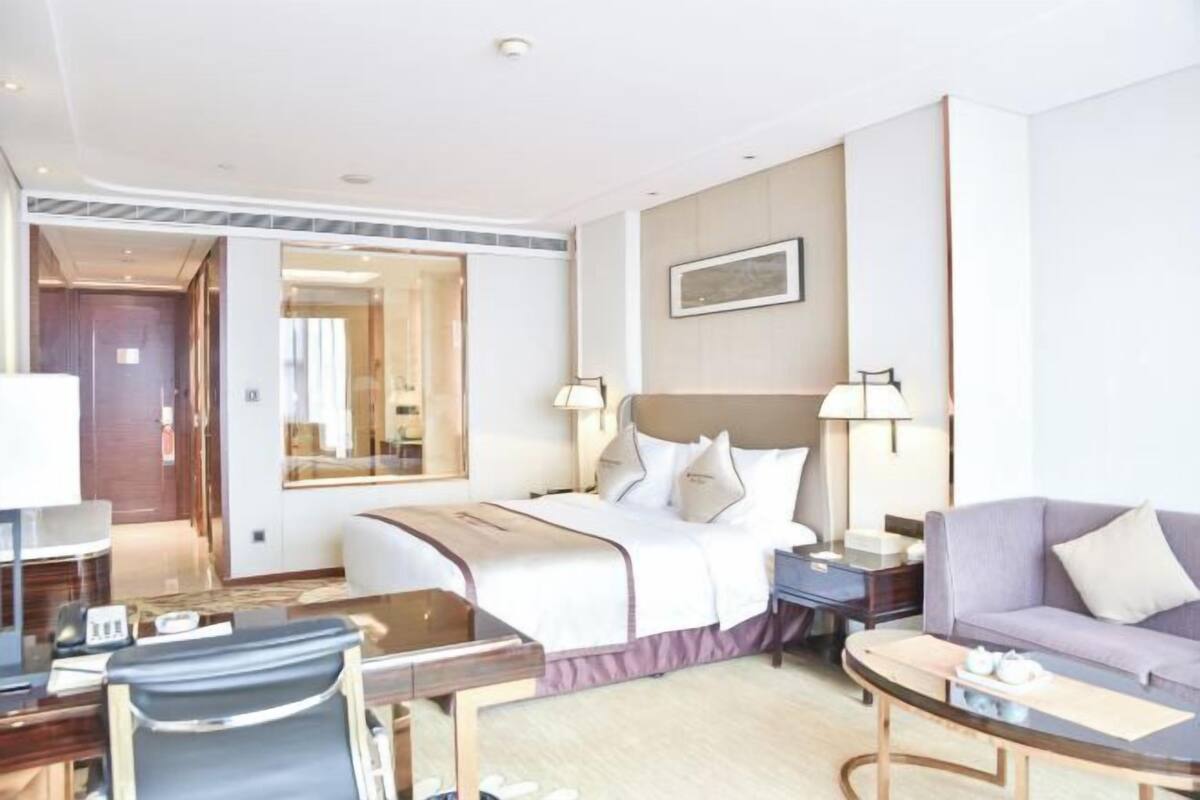 Une chambre d’hôtel comprenant un lit, un bureau, une chaise, un canapé et une table de chevet.