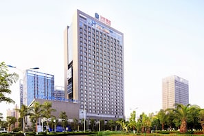 Um edifício alto de hotel com uma grade de janelas e uma placa no topo.