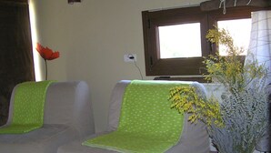 Ένα δωμάτιο με δύο καρέκλες, ένα παράθυρο και ένα βάζο με λουλούδια.