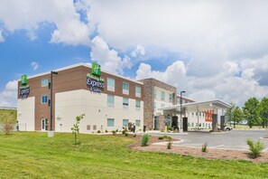 A Holiday Inn Express & Suites hotel with a modern design, featuring a flat roof, large windows, and a covered parking area.