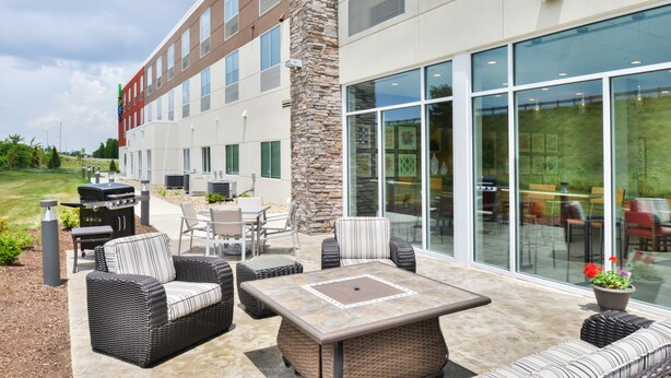 An outdoor patio area with wicker furniture, a stone pillar, and a glass-enclosed dining area. - Holiday Inn Express & Suites Salem by IHG (Salem)