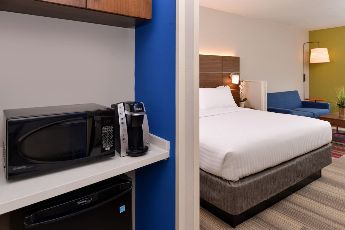 A hotel room with a microwave, coffee maker, and a bed.